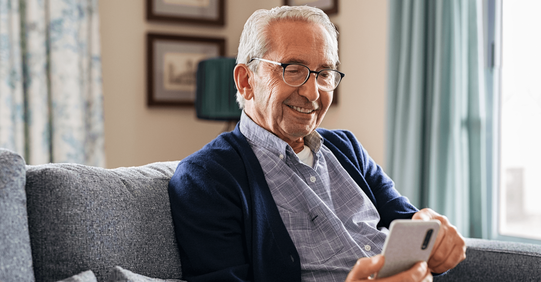 Man sitting on couch looking at a financial planning software client mobile app on his phone